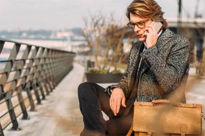 Man outside sitting on bench on cell phone